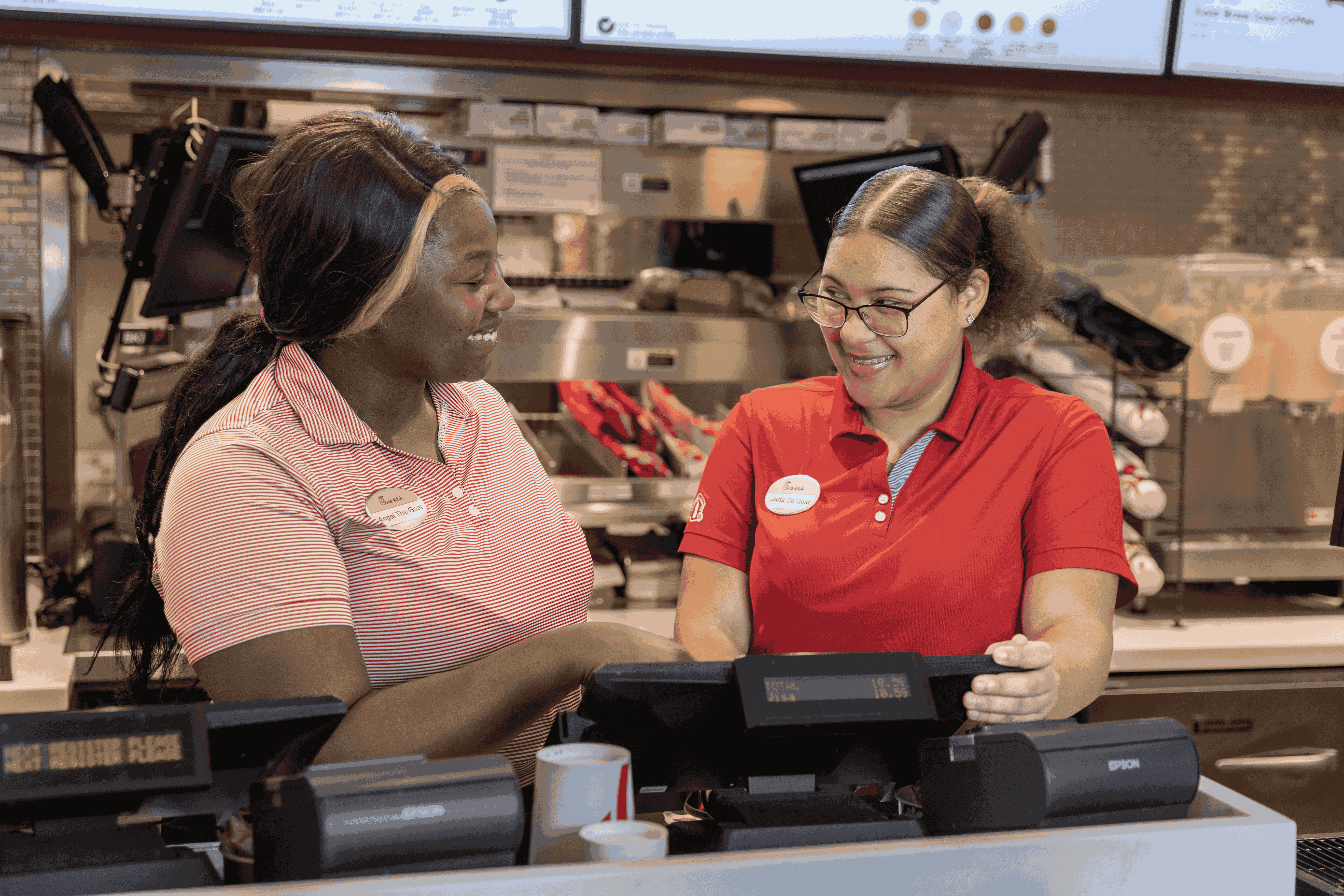 Two front of house team members smiling at each other